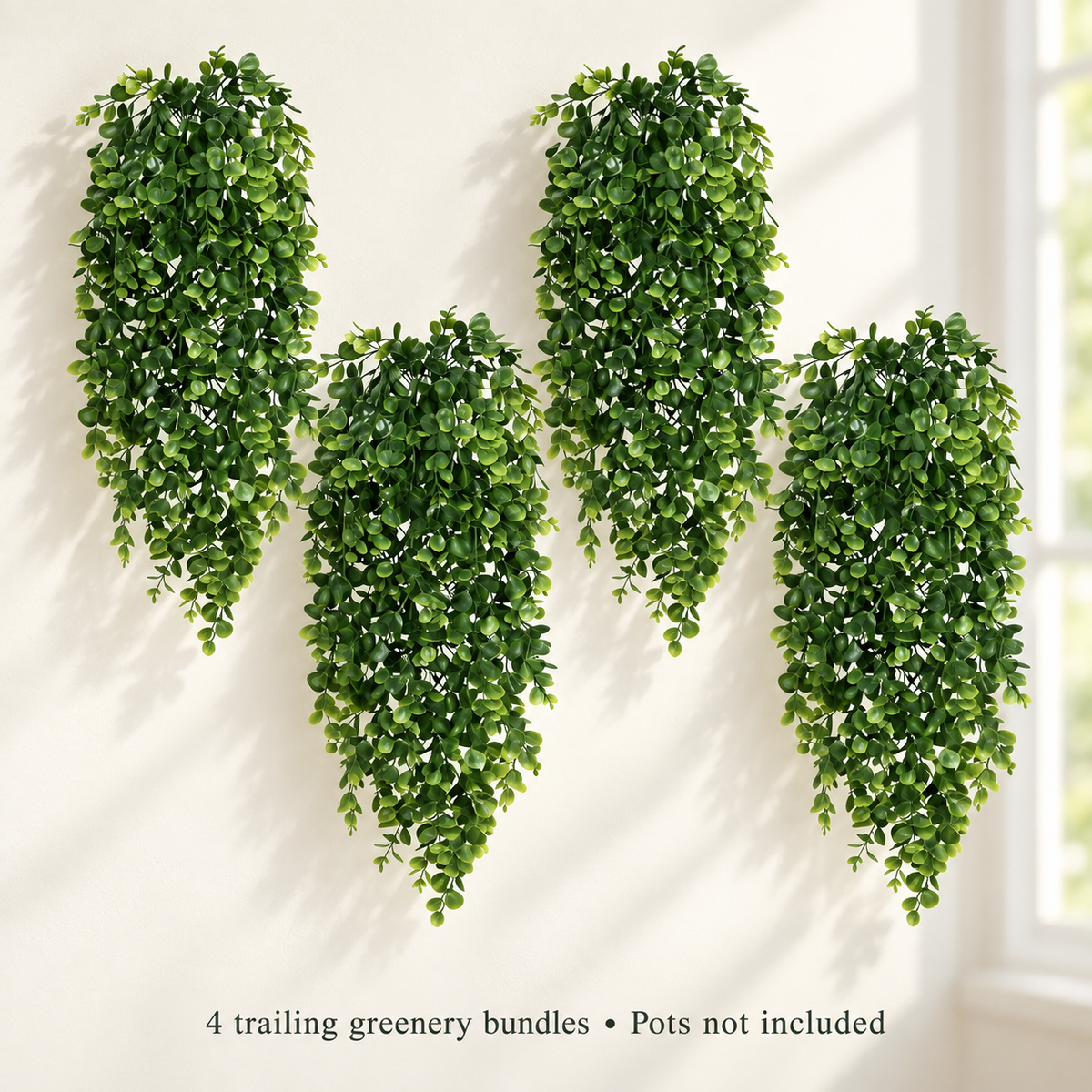 Four trailing artificial greenery bundles with small oval leaves — window light