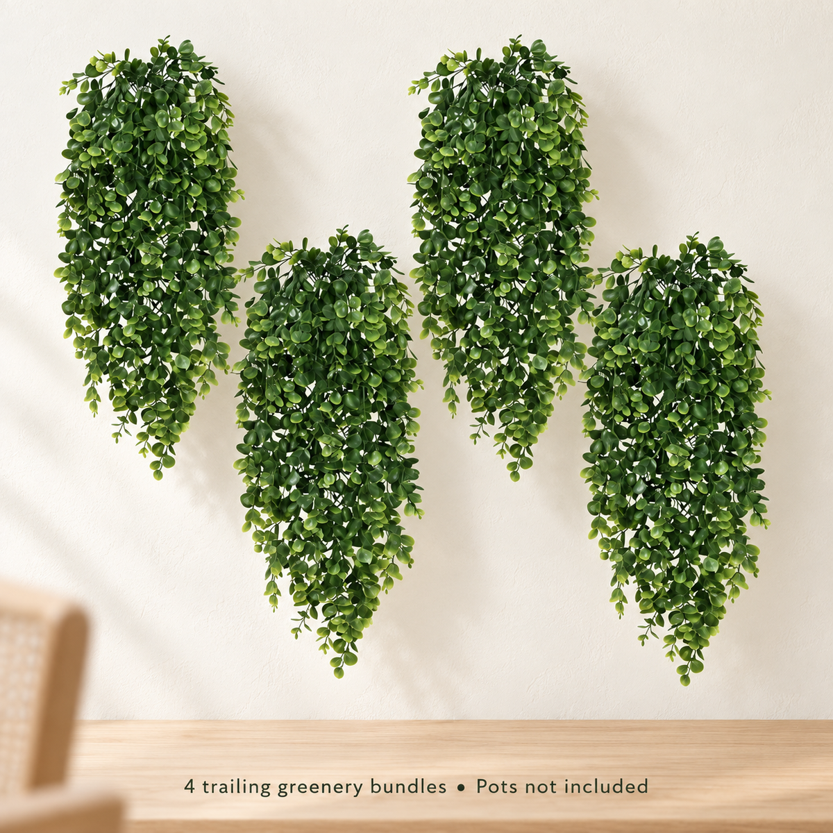 Four trailing artificial greenery bundles with small oval leaves — minimal room