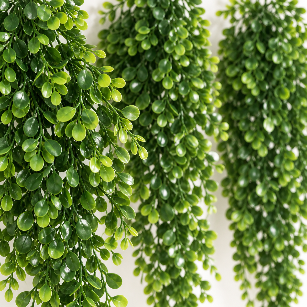 Four trailing artificial greenery bundles with small oval leaves — color detail