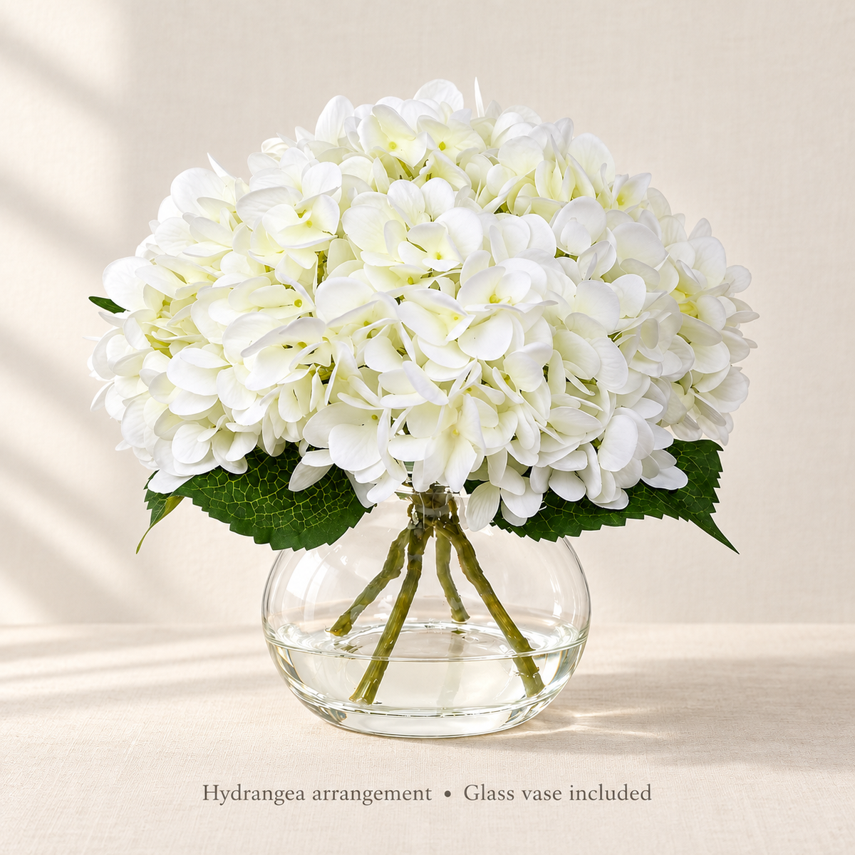 White hydrangea arrangement in glass vase with faux water — airy portrait